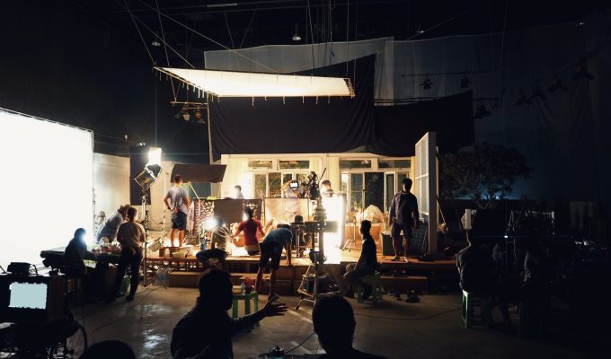 Silhouette of people working in big production studio for shooting or recording movie video by digital camera and lighting set.